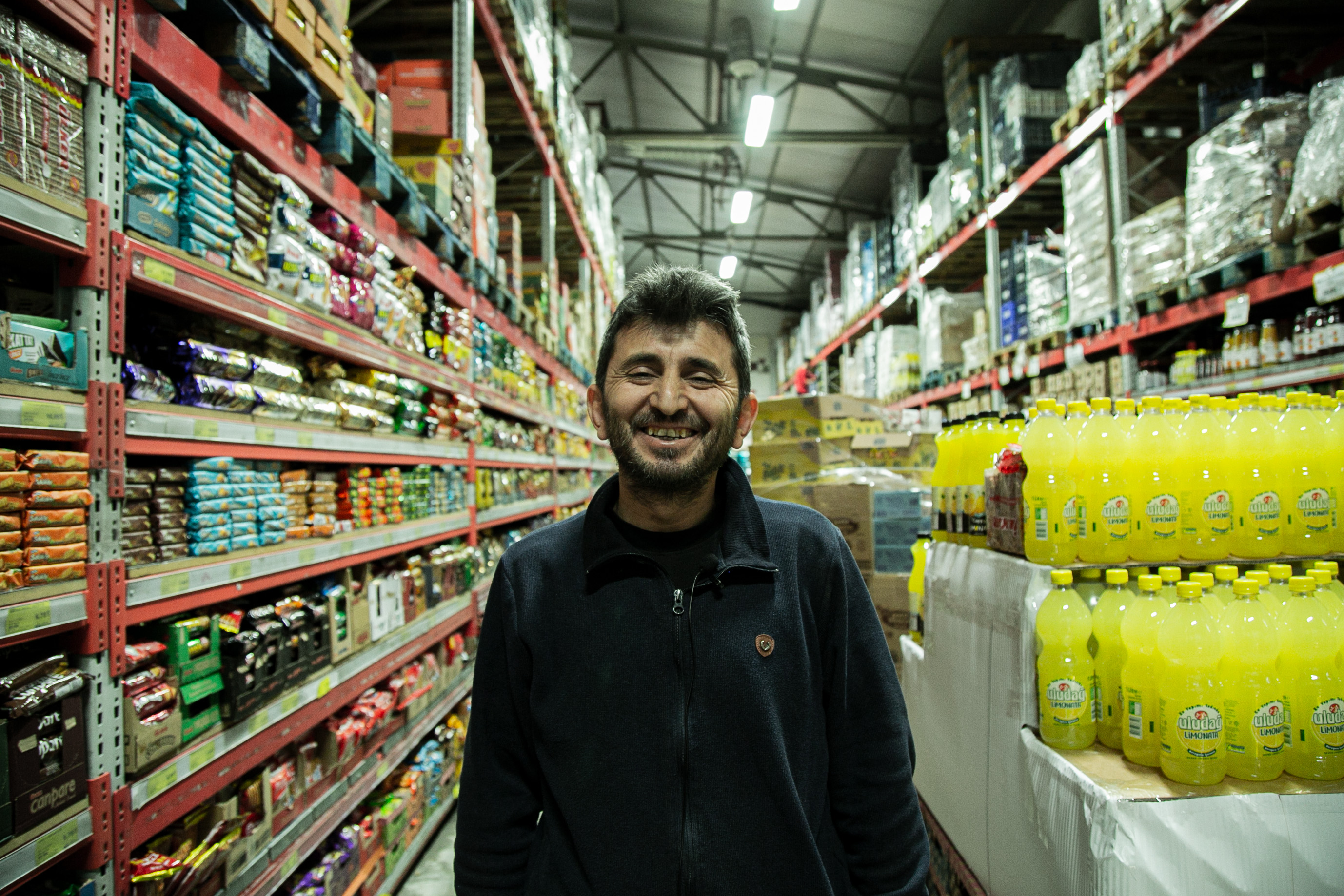 Gultekin, a store owner, feels happy in his store in Kahramanmraş after his sales improved thanks to DRC's Cash and Voucher Assistance (CVA) response in March 2023. CVA response partnered with local stores to ensure access to essential goods to those in need. 