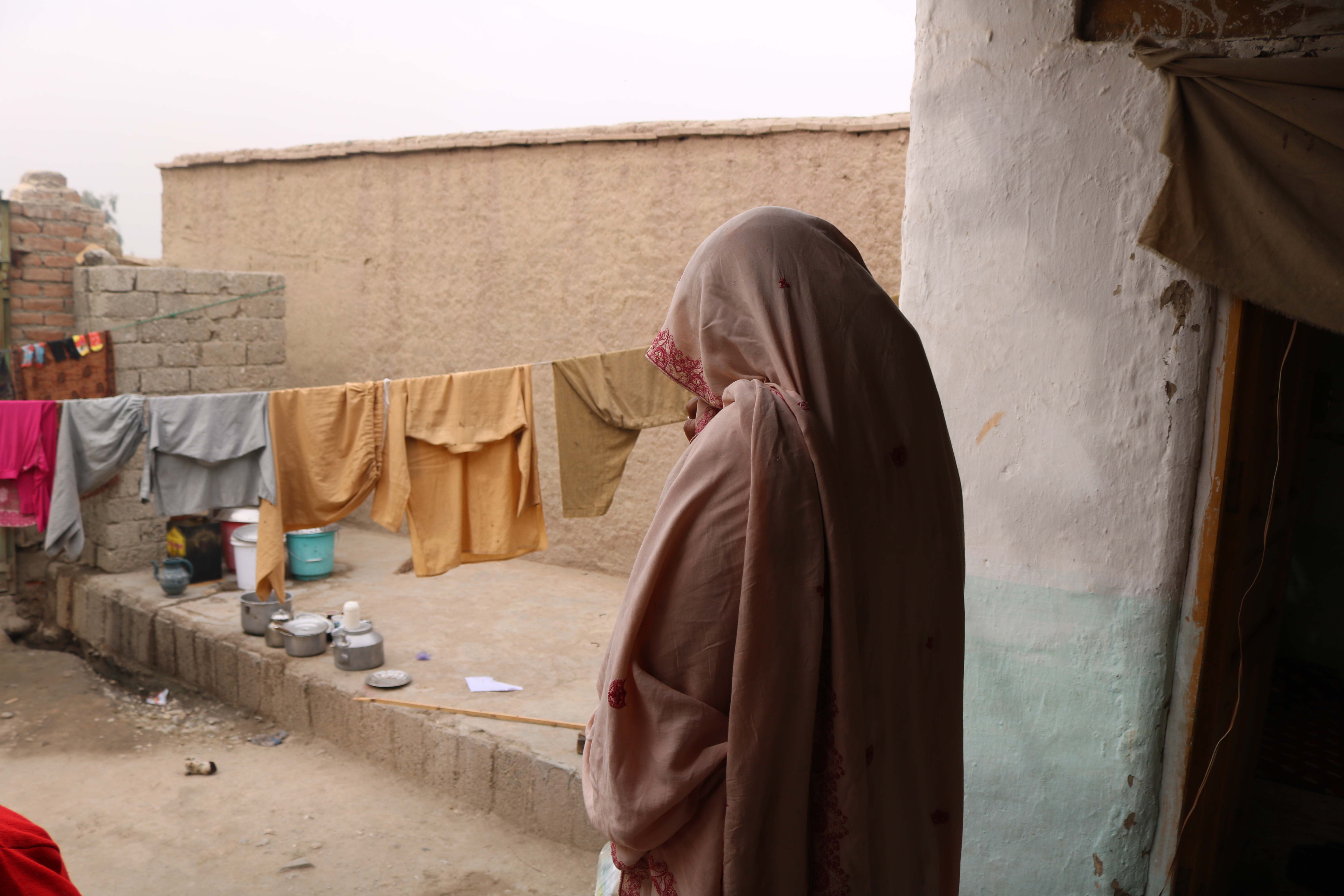 Mariam is telling us her story in the open area of her house in an IDP settlement that she can barely afford. Kuz Shekh Mesri Camp, Jalalabad, Nangarhar. 26 November 2023. @DRC, Manon Radosta 